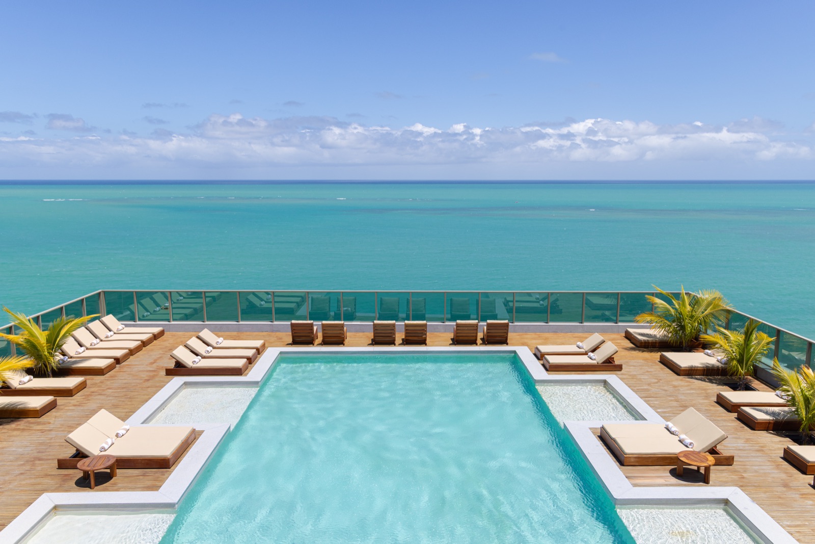 Piscina do rooftop do Sais Beach Living com espreguiçadeiras e vista para o mar da Pajuçara